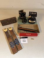 Full view of all items including ink bottles, wooden-handled fountain pen, Esterbrook pen in red box, ink stamp, and drawing leads.