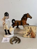 Four items on a neutral background: Feeding Time Coalport figurine, brown horse figurine, horse block picture, and brass horse ornament showing detailed horse shape and patina.