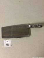 Full view of the large rounded rectangular blade cleaver with metal handle and seller lot number card visible.