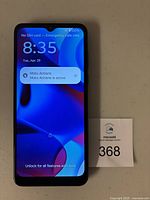 Front of powered on Motorola Moto G smartphone with screen on and Moto Actions notification displayed.
