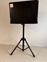 Full front view of the black metal music stand showing adjustable height and tripod legs.