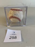 View of the signed baseball inside the clear display box from an angle showing the signature.