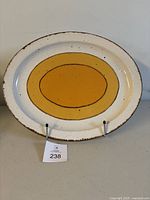 Full view of oval platter displaying distinctive Midwinter Sun pattern in mustard and brown tones on a white background.