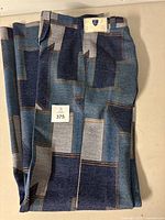 Full folded view of the patchwork pants on a flat surface showing front with patchwork colors and stitching visible.