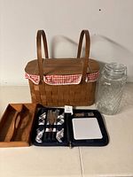 Vintage picnic basket and accessories including lemon container, wooden tray, and utensil set.