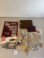 Photo of the full assortment showing the two albums, loose stamps in plastic packs, butterfly themed page, and various stamp bundles spread out on a table.