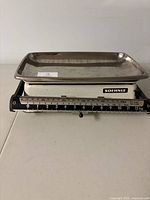 Side view of the vintage Soehnle balance scale, showing the sliding weight mechanism and measurement markings up to 12 kg on the base, with the metal tray on top.