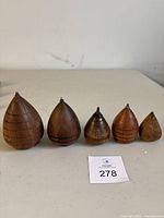 Set of five vintage wooden spin tops with metal tips and painted horizontal rings, varying sizes