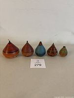 Full set of five vintage wooden spin top toys in various colors and sizes arranged in a row on a white surface.