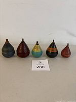 Full set of five vintage wooden spin tops arranged in a row, showing variety in colors and hand painted details.