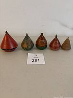 Front view of all 5 wooden spin tops arranged in a row, showing colors and wear.