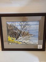 Framed watercolor painting of Scarborough Bluffs in winter, showing landscape with leafless trees, snowy rocks, ocean and cloudy sky. Signed by artist Glen Lush in lower right.