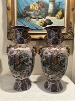 Full front view of both vases side by side on tabletop with framed still-life painting background