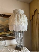 Tall vintage Italian crystal table lamp with cream-colored ruffled fabric shade and fringe, ornate metallic base.