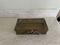 Top view of rectangular vintage tissue box cover showing ornate gold filigree metalwork and tissue opening.