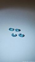 Four natural oval cut seafoam blue Cambodian zircons shown under light on white background to display clarity and color.