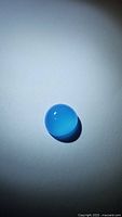 Close-up photo of the natural round blue chalcedony gemstone with translucent icy blue color and polished cabochon surface.