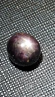 Oblique top view of oval purple star sapphire on textured background
