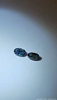 Two oval cut natural blue sapphires with deep and lighter blue hues on white background showing clarity and shape.