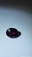 Close-up photo of the natural untreated oval cut spinel showing deep purple color and faceting details.