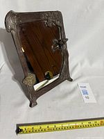 Angled side view showing the rectangular mirror with ornate frame highlighting floral motifs and Lady of the Lake figure integrated into design.