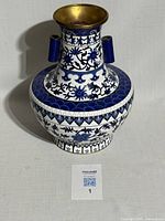 Full front view of the antique large cloisonne vase showing blue and white floral patterns and brass interior.