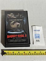 Black clamshell VHS case with front cover showing Basket Case 3: The Progeny movie artwork and title. Tape case measures approximately 7.5 inches tall.
