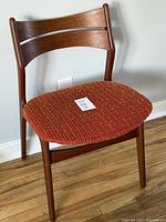 Front view of the Danish Mid Century Modern teak chair showing the orange fabric seat and curved backrest slats.