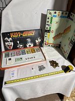 KISS-opoly game box, board laid out, various playing pieces, cards, money, dice, and instructions shown on a white surface