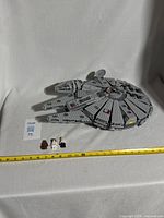 Full Millennium Falcon set with three minifigures and measuring tape for size reference.