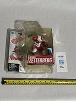 Front of new Henrik Zetterberg NHL Sports Series 14 action figure in packaging, showing white jersey variant and Red Wings logos.