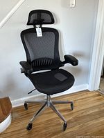 Front angle of black mesh office chair showing headrest, seat and armrests.