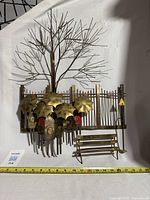 Full view of the metal wall sculpture showing tree, fence, umbrellas, bench and lamppost
