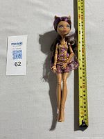 Full body photo of Monster High Clawdeen Wolf doll lying next to measuring tape showing length about 10.5 inches.