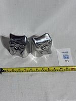 Front side of paired owl bookends, showing owl faces and measuring tape indicating size