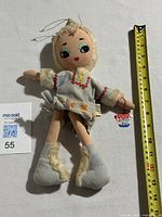 Full front photo showing the entire cloth doll in an Inuit-style fur-trimmed outfit alongside a measuring tape for scale, approximately 12 inches tall.