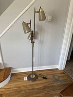 Full frontal view of lamp showing three shades, central rod, round base