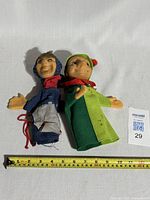 Two vintage hand puppets side by side, showing full length and size with measuring tape indicating about 10 inches tall