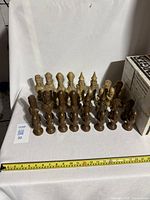 Full view of all chess pieces arranged in rows by color, showing a completed set of 32 pieces of varying detail and sizes.