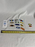 Twelve Murano art glass candy-shaped figurines arranged with a tape measure showing sizes around 1.5 to 2 inches