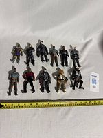 Photo showing all 12 Star Trek action figures arranged on a white backdrop with measuring tape showing approximately 6 inches for scale.