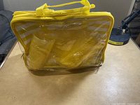 Picnic set inside clear plastic and yellow striped carrying tote with handles