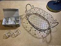 Set of six clear glass napkin rings displayed next to the decorative wire basket.
