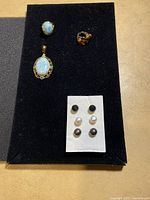 Full lot overview showing pendant, two rings, and six stud earrings on black display board