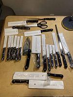 Full spread of entire 22-piece cutting utensil set showing knives, shears, and sharpening steel with most items partially or fully wrapped in their original packaging.