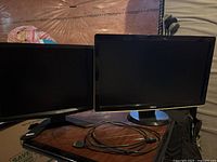 Both Acer and Dell monitors shown side by side with a single HDMI cable coiled between them on a wooden surface.