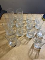 Top view of all 14 clear glass pieces arranged on a surface showing varied heights and similar design.