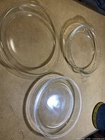 Three clear glass pie plates displayed on a flat surface showing different sizes and shapes.
