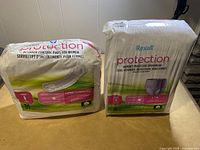 Two packs on a flat surface, one pack of bladder control pads with 39 pieces and one pack of Rexall Protection women's protective underwear with 18 pieces size L/G.