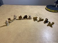 Wide view of all 10 small figurines arrayed on tabletop, showing general size and color variations among the lot.